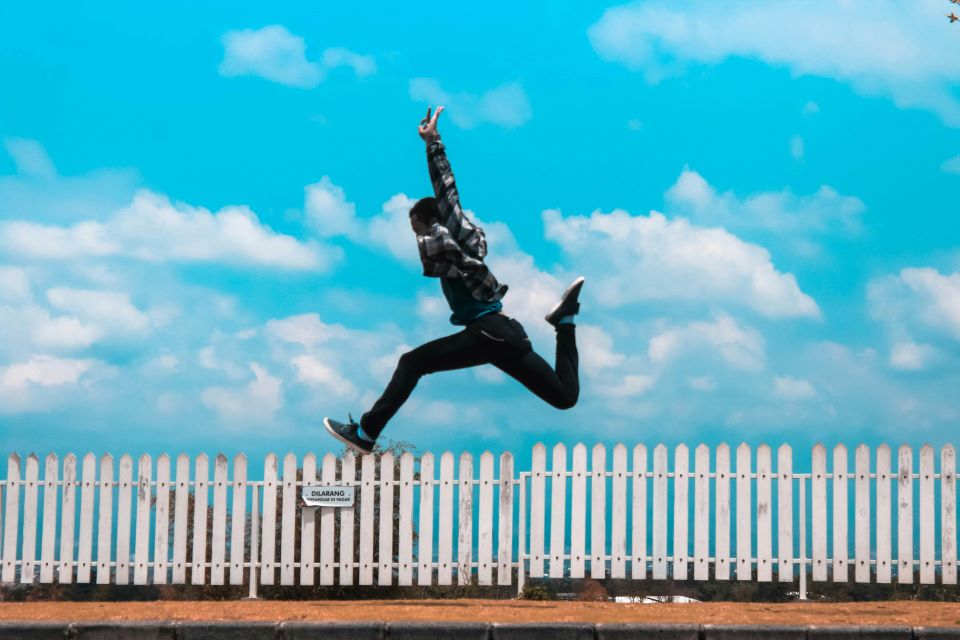 Man jumping over white fence