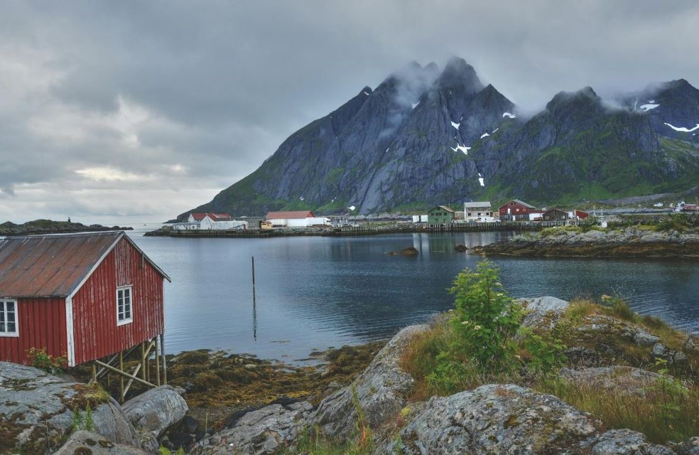 Red Wooden House Near a Mountain and River during Daytime